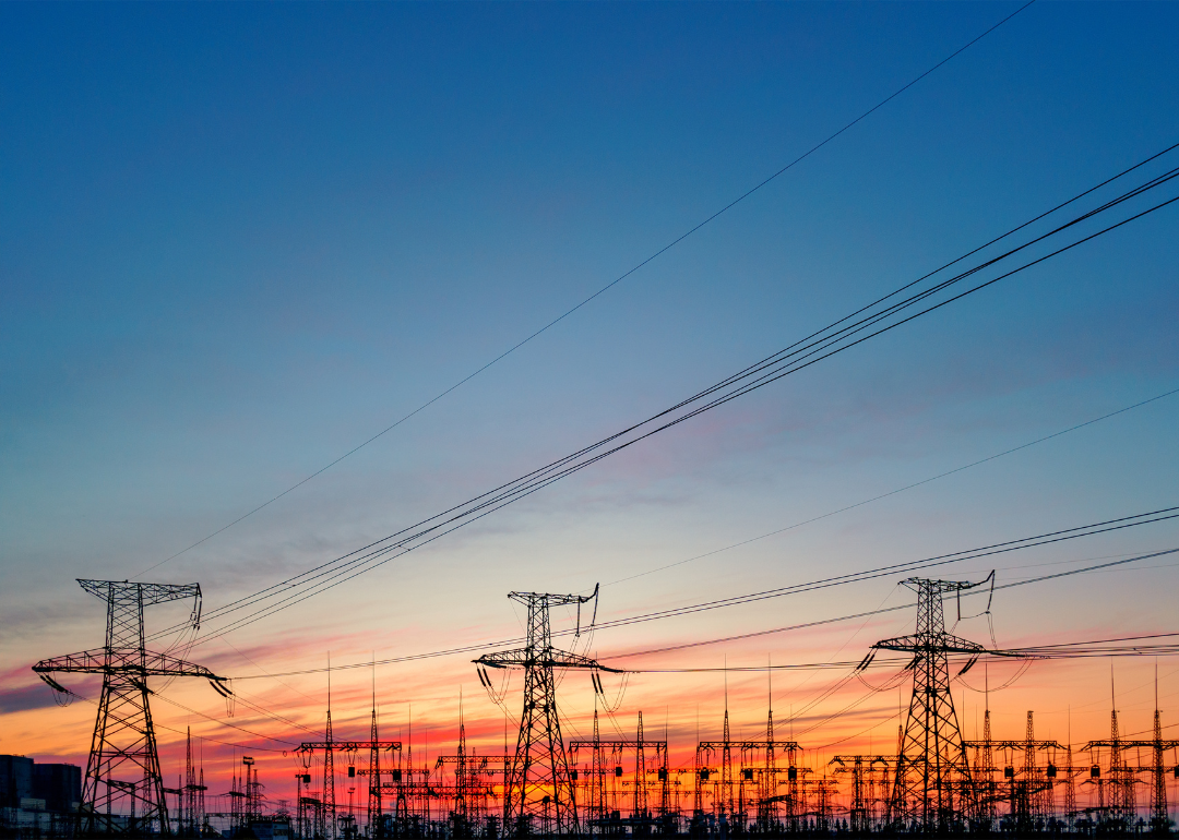 A high-voltage power grid with a sunset in the background.