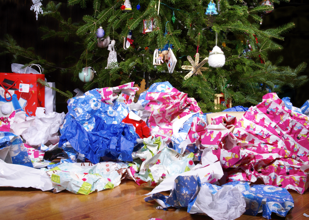 A mess of wrinkled wrapping paper scattered under a Christmas tree
