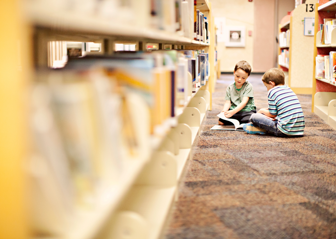 Two kids reading together in a library.