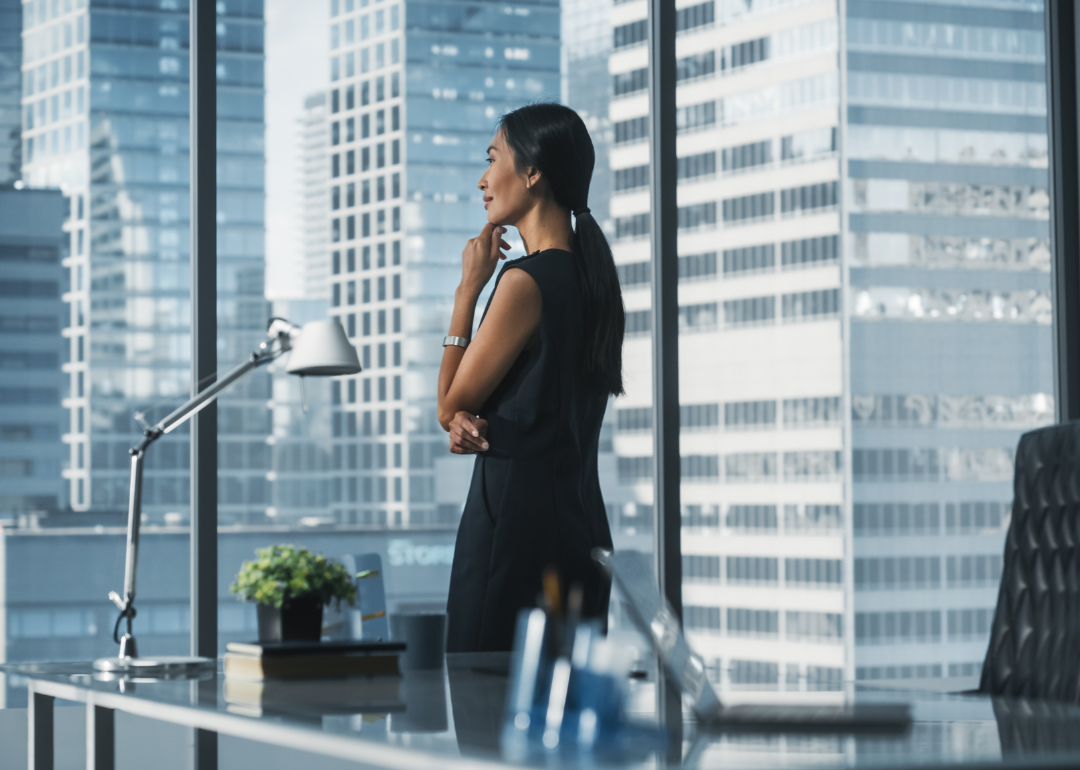A woman looks out the window of an office building.