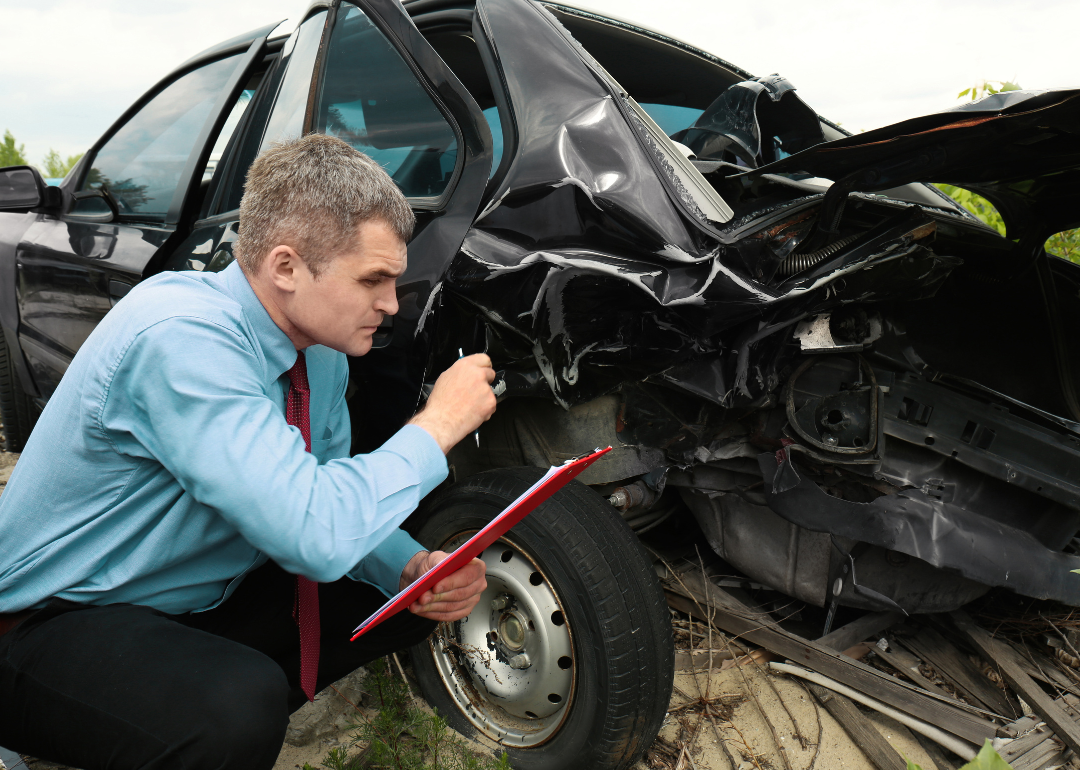 An adjuster assessing a severely damaged vehicle.