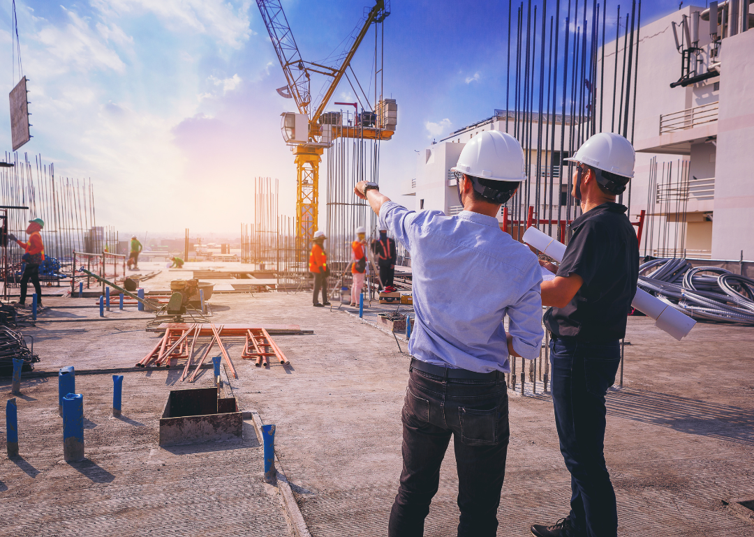 Two construction workers with blueprints at a building site