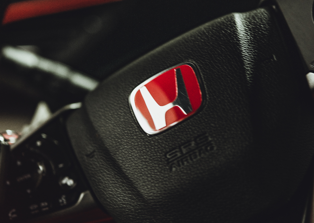 A closeup of the Honda logo on a steering wheel.