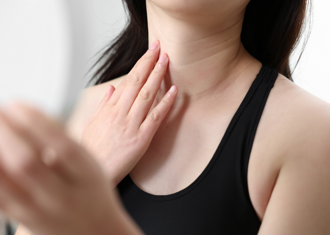 A person holding their neck while looking in a mirror.