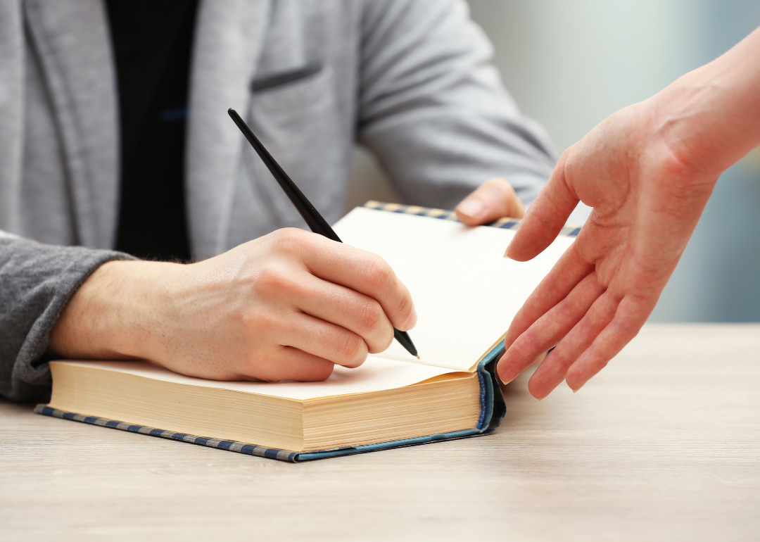 An author signs a copy of a book.