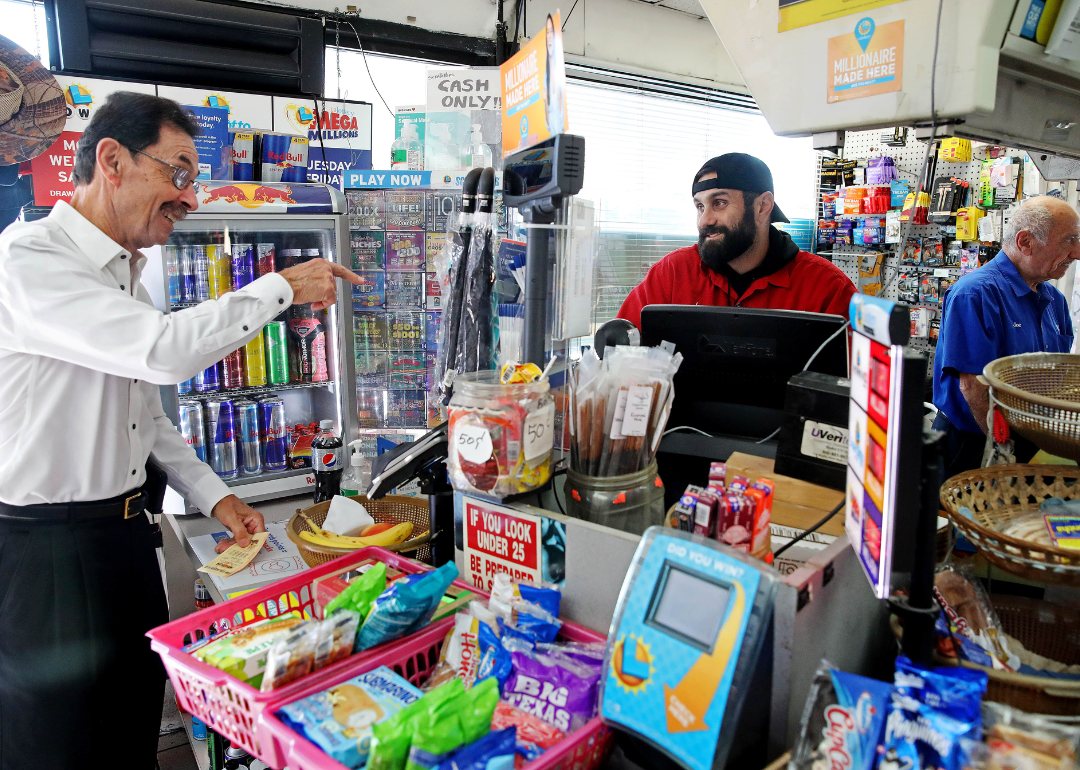 A person behind a counter at a service station talking to a customer.