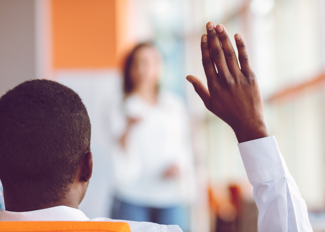 A businessperson raising their hand in a meeting.