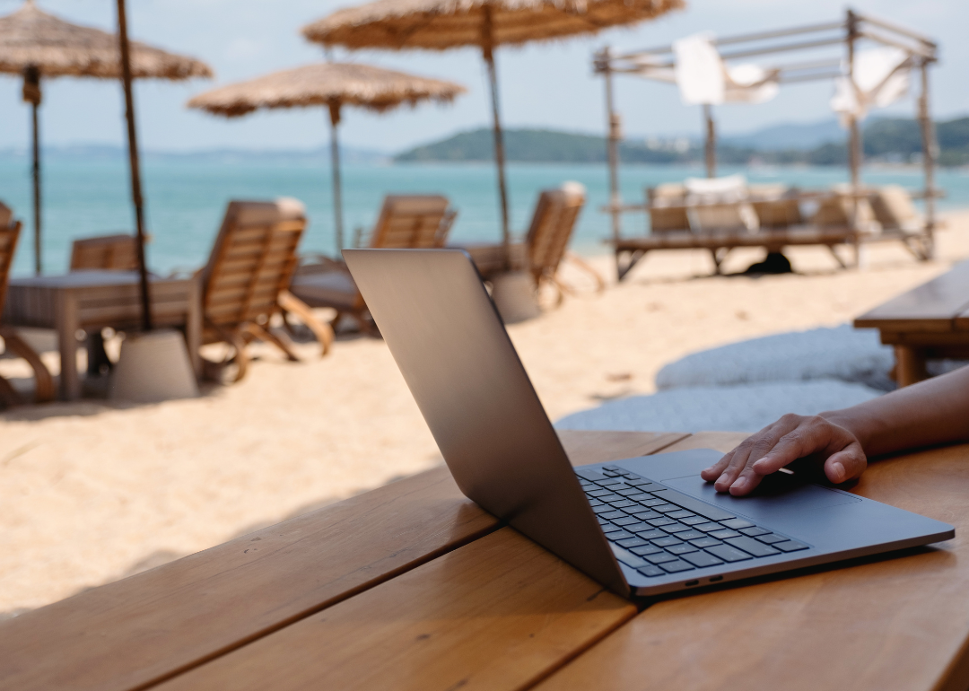 A person doing work on a laptop while at the beach.