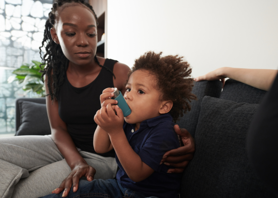 A young Black child using an inhaler when having asthma attack