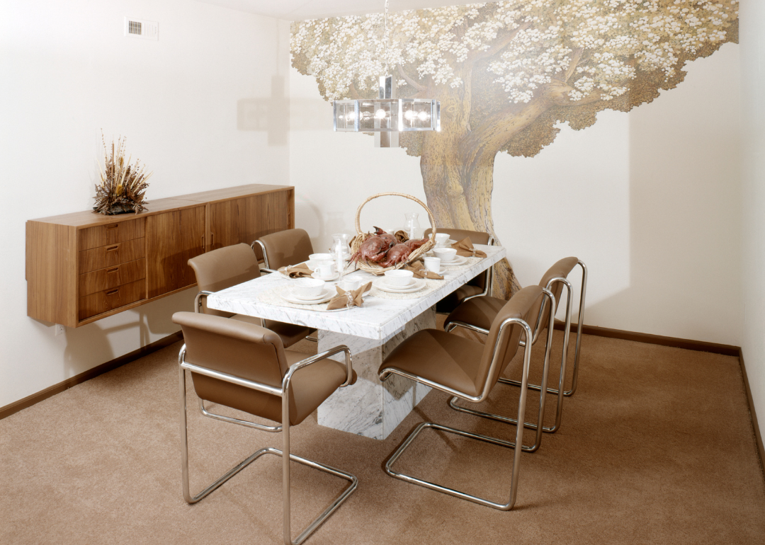A dining room with a mural of a tree in 1977.