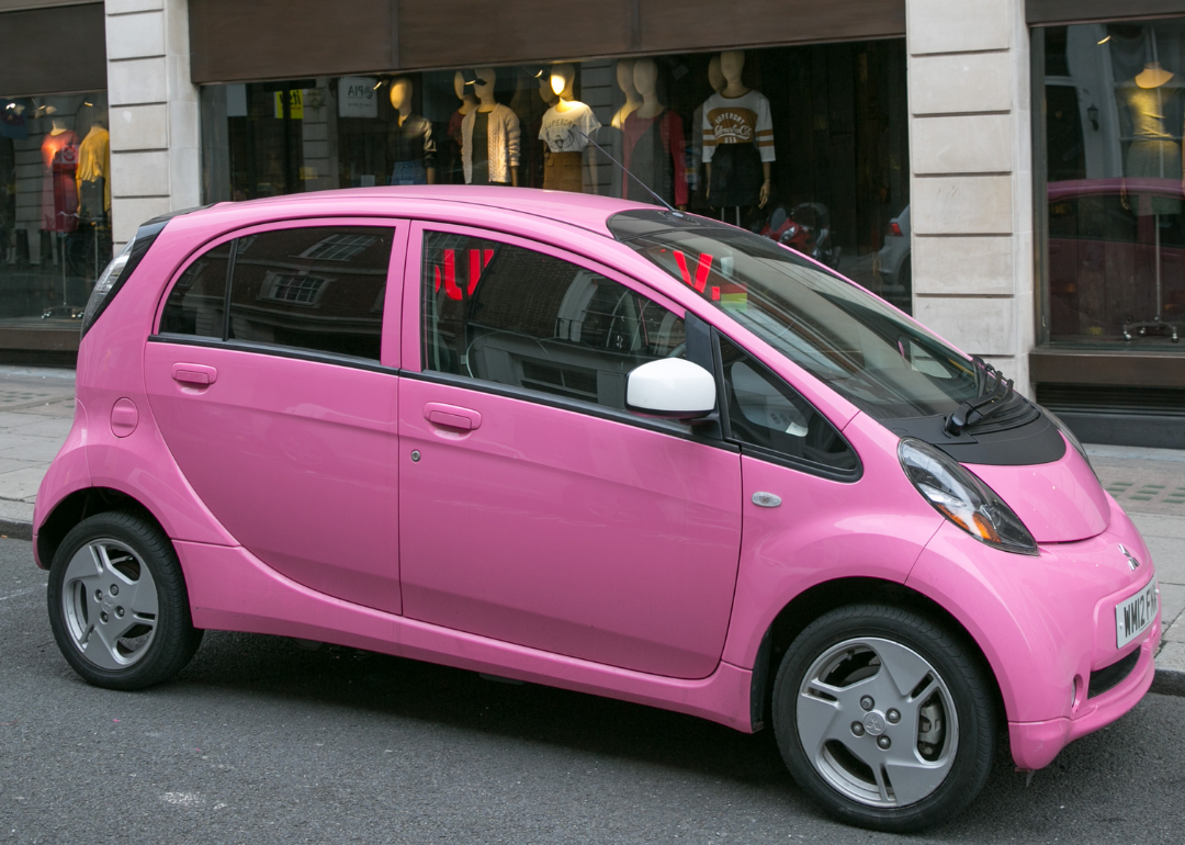 A pink Mitsubishi iMieV parked along a side street near the Royal Academy of Arts.