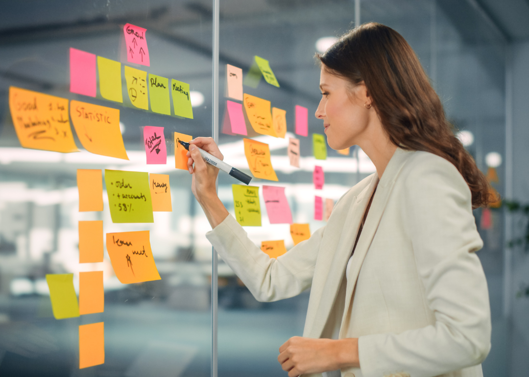 A marketing specialist writing on sticky notes during a brainstorm