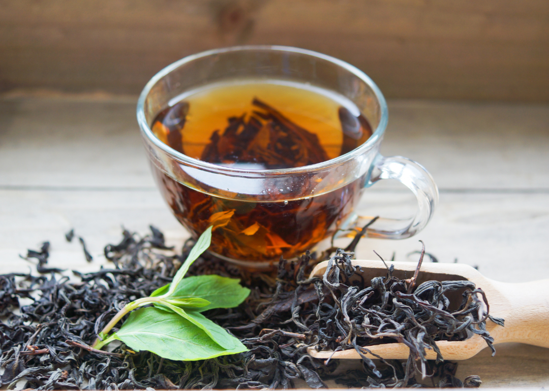 A clear glass mug of black loose-leaf tea.