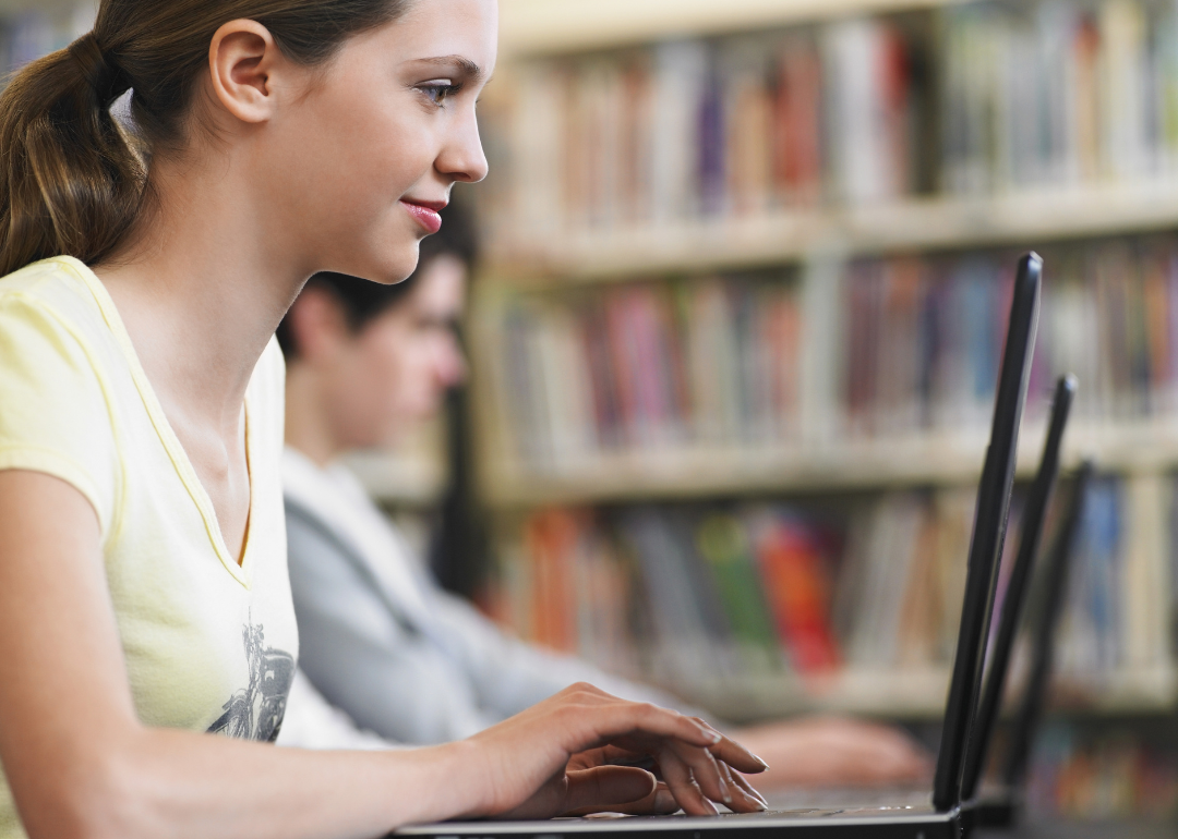 A side view of a person using a laptop in the school library.