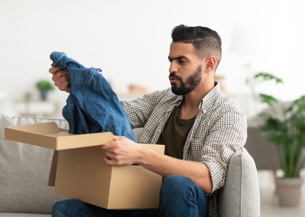 A man unhappily unboxing a carton package of clothes