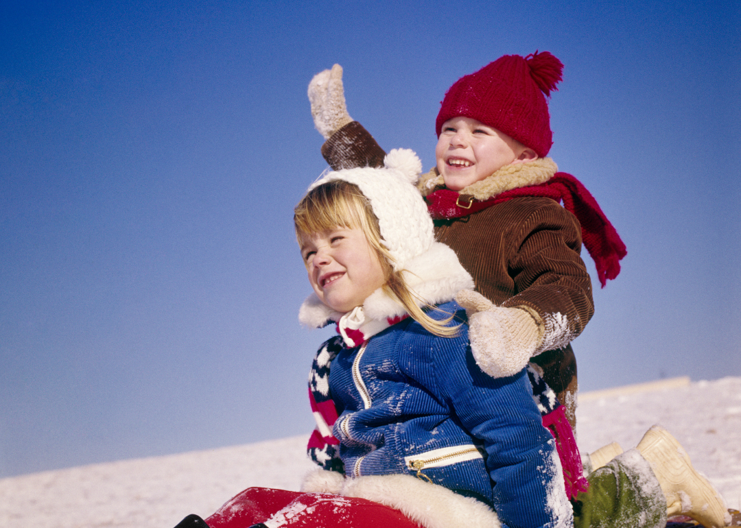Two children smiling on a sled.