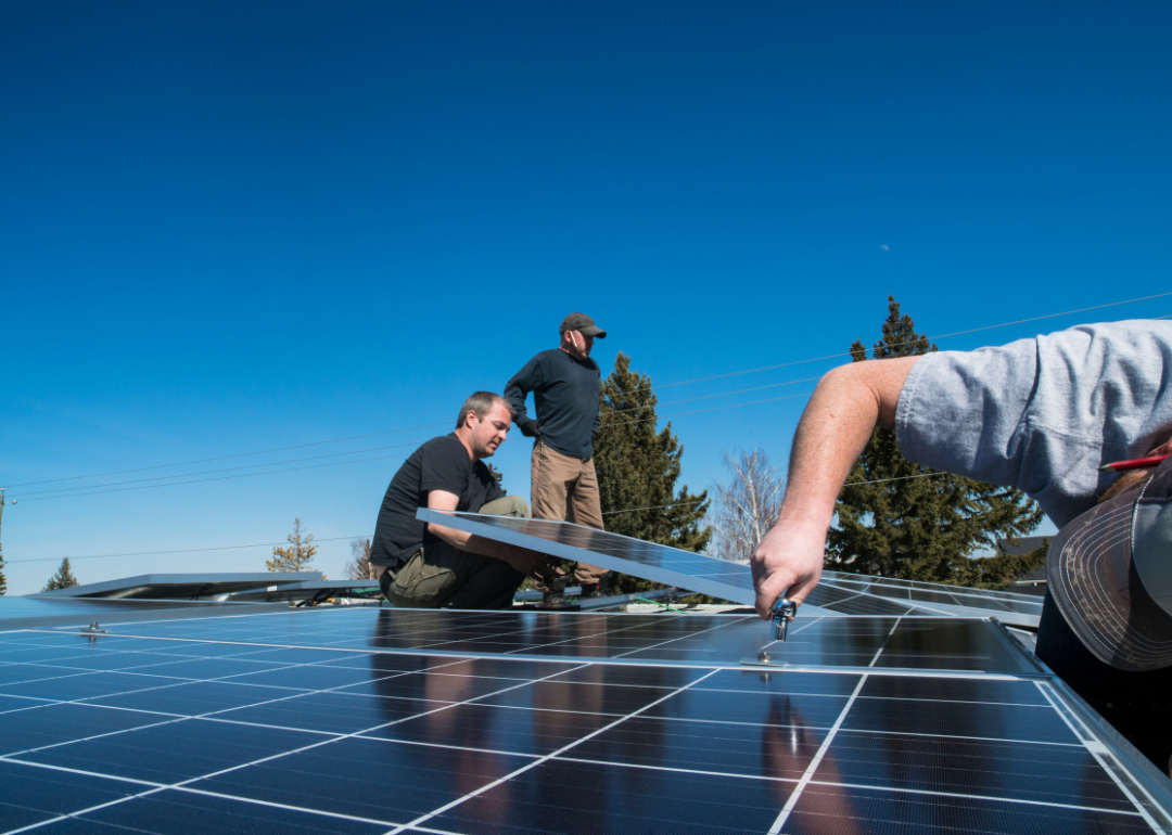 Workers installing solar panels on a home