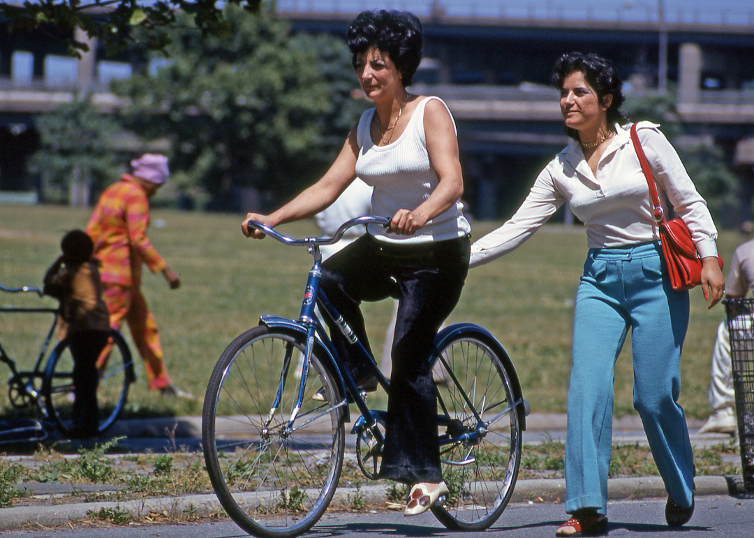 A person steadying the bike of a friend learning how to ride.