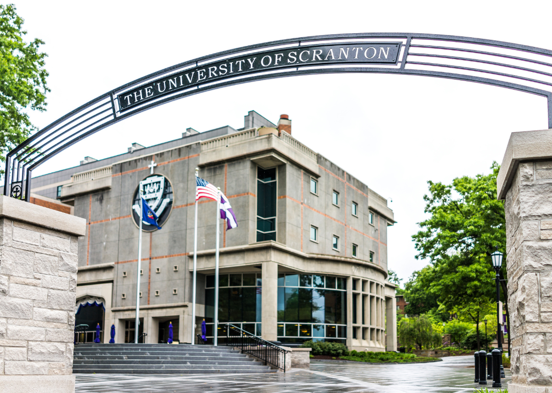The University of Scranton library building with an entrance sign and flags.