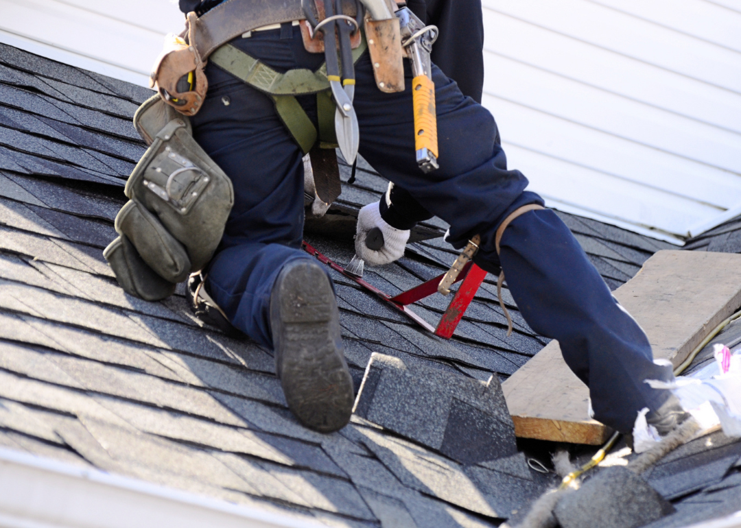 A roofer installs composite shingles