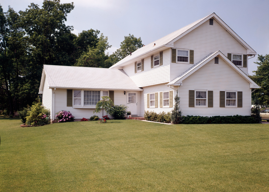 A white suburban home with olive shutters in 1972.