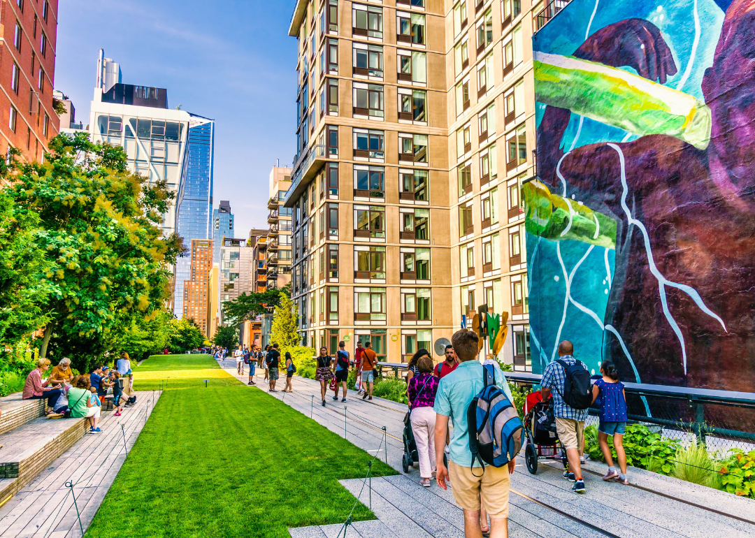 People walking down the High Line and observing public art installations.