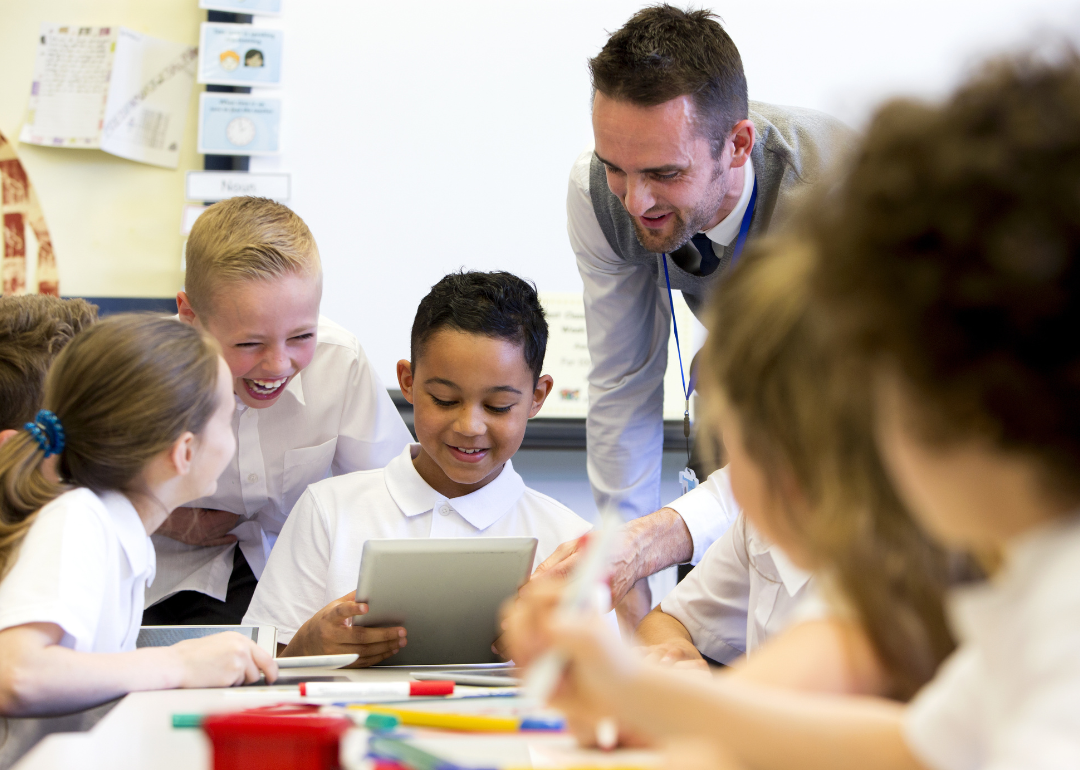 A teacher listening to a group of children.