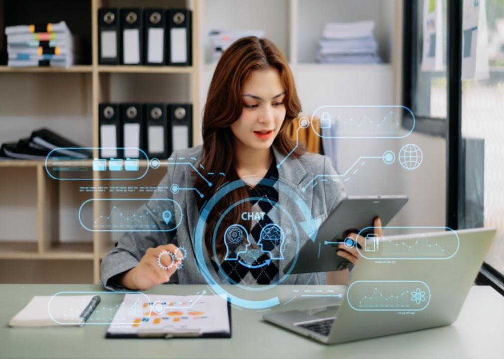 A young woman looking at an iPad in her hand in an office.