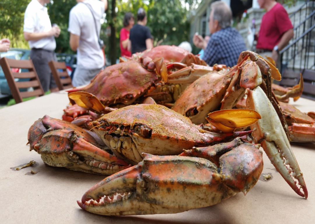 Steamed crabs on a restaurant table with people in the background.