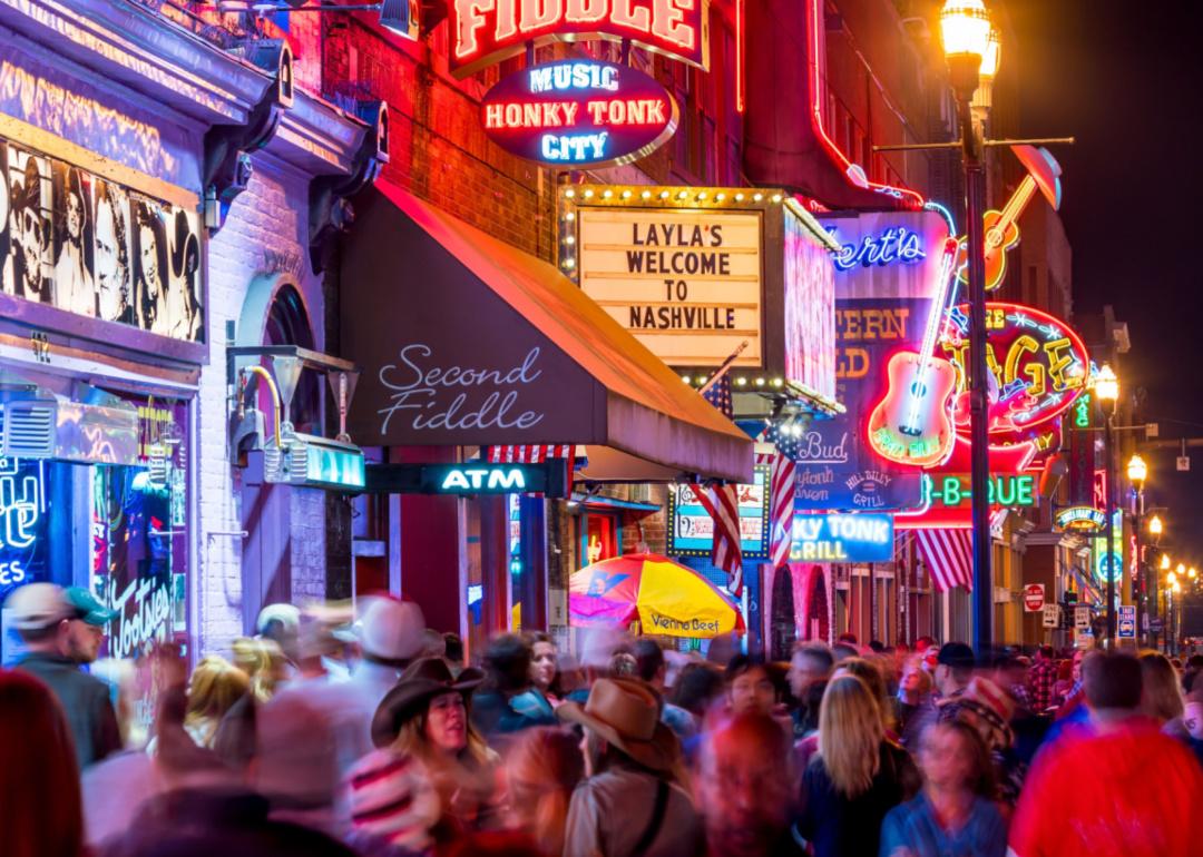 Crowds of people on the streets of lit up Nashville.