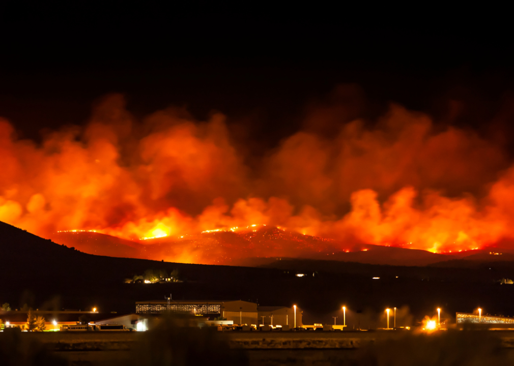 A large fire burning on the side of a mountain at night.