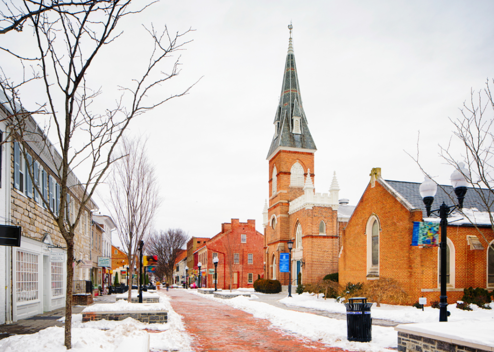 A snowy street with predominantly low red brick buildings on both sides. 