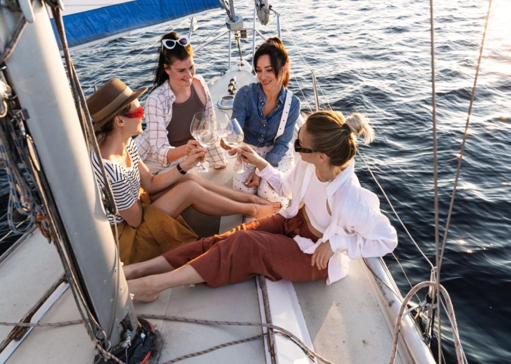 Four youthful women recline on a boat, each gracefully holding a wine glass.