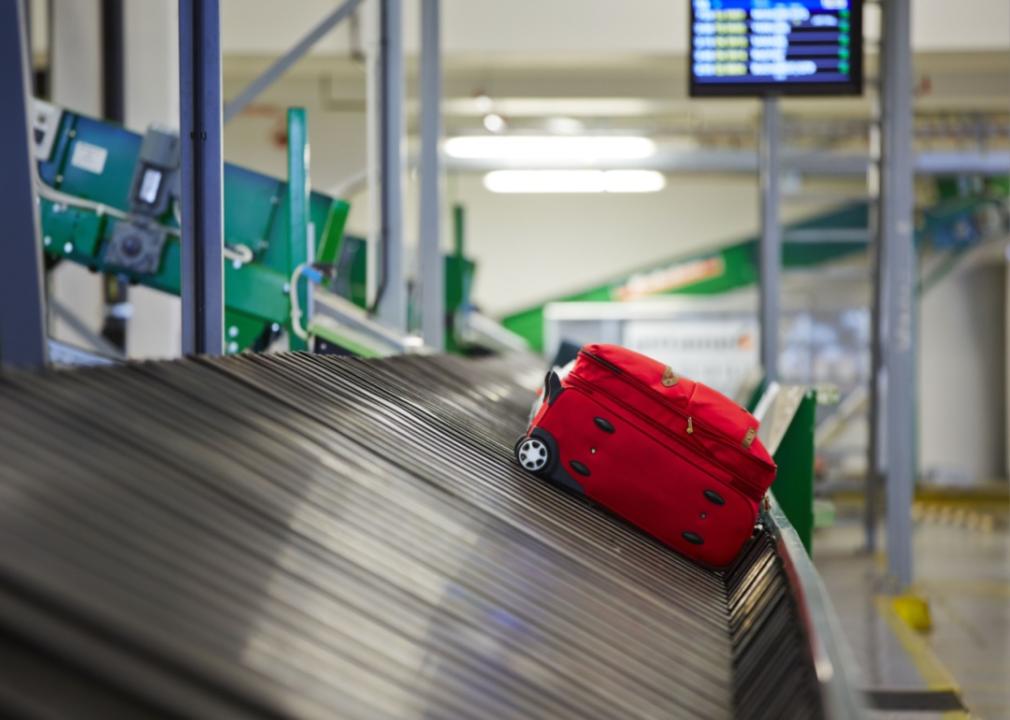 A red suitcase on a baggage belt.