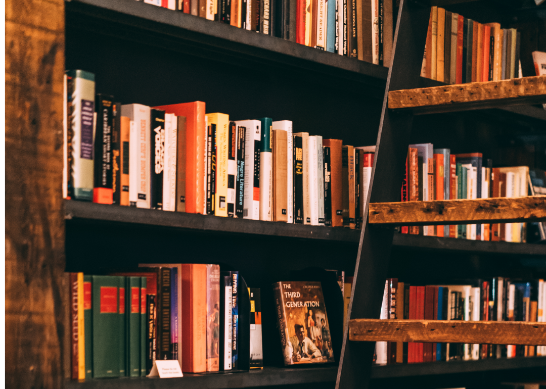 Books in an old library on wooden shelves.