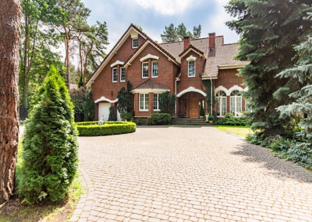 A brick mansion with a cobblestone driveway.