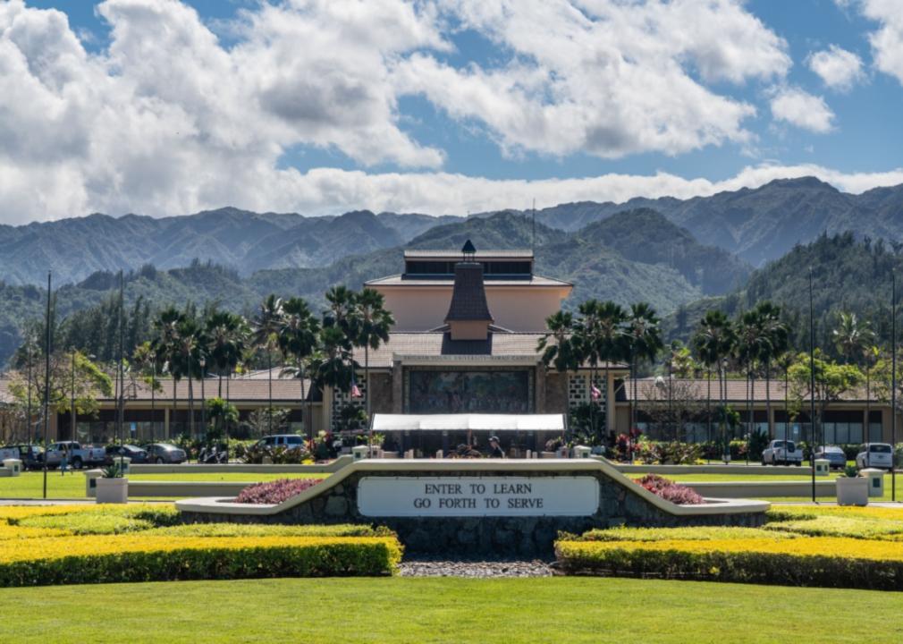 The entrance to Brigham Young University lined with palm trees and mountains in the background.