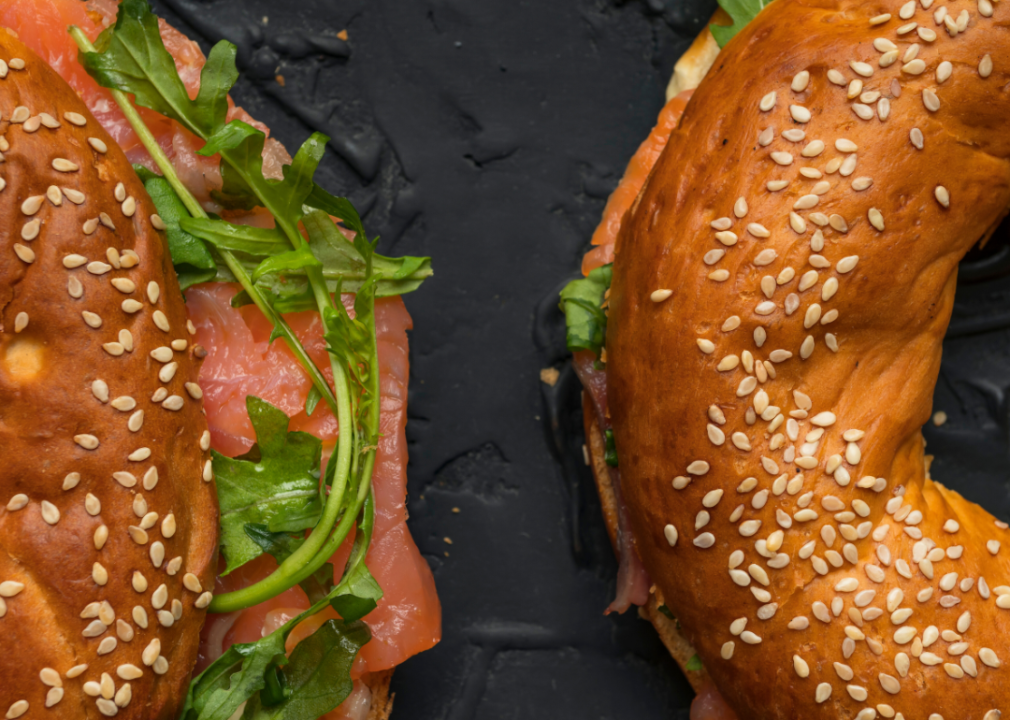 Two halves of a breakfast bagel sandwich with smoked salmon and arugula.