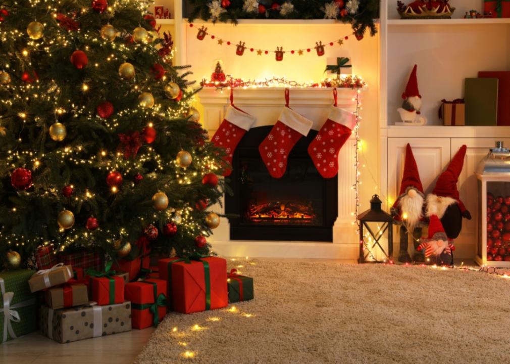 A Christmas tree with lights and presents in a decorated living room.