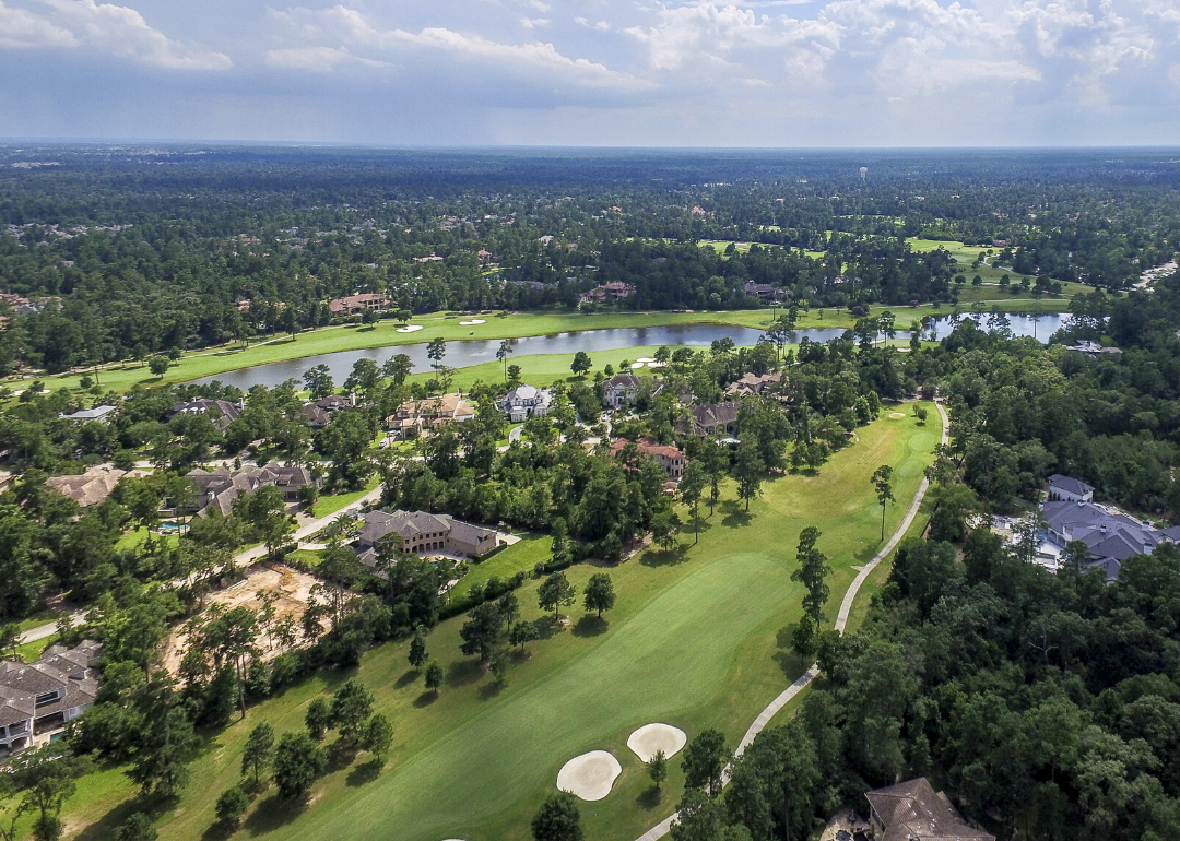An aerial view of homes on a golf course near water.