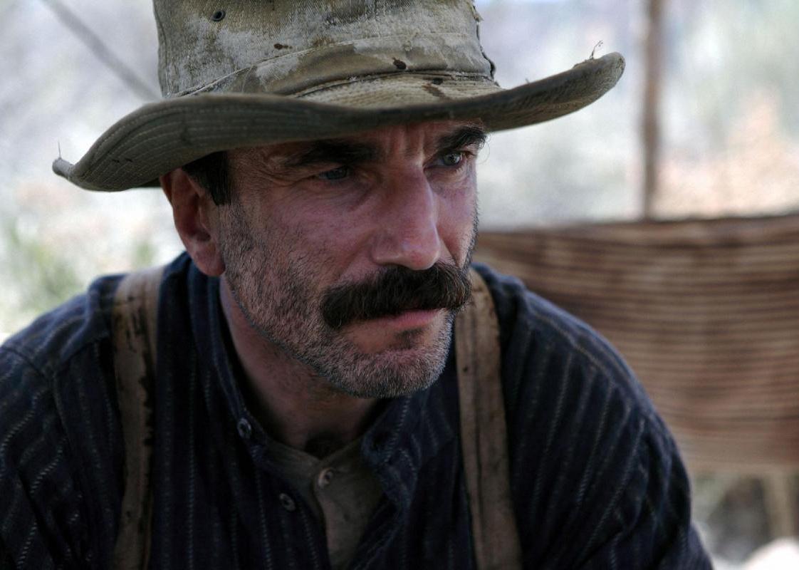 Daniel Day-Lewis in a blue shirt with suspenders and a tattered western hat.