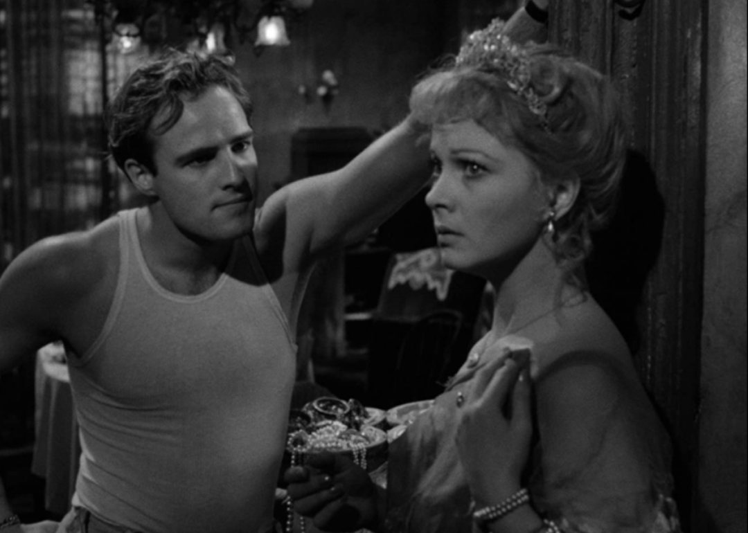 Marlon Brando in a white tank top looks seriously at a woman.