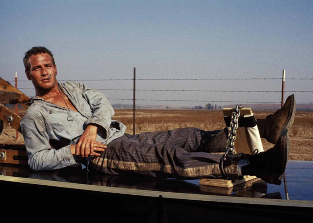 Paul Newman lying down with his legs chained together.