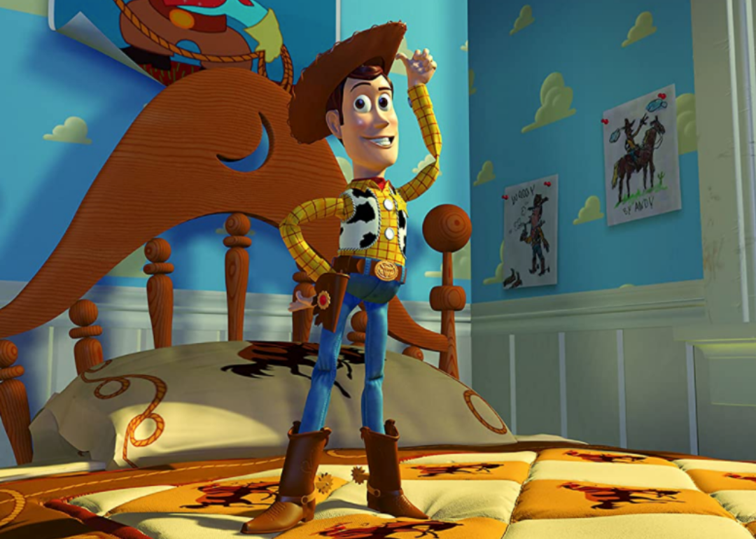 A cartoon cowboy smiling and standing on a bed.