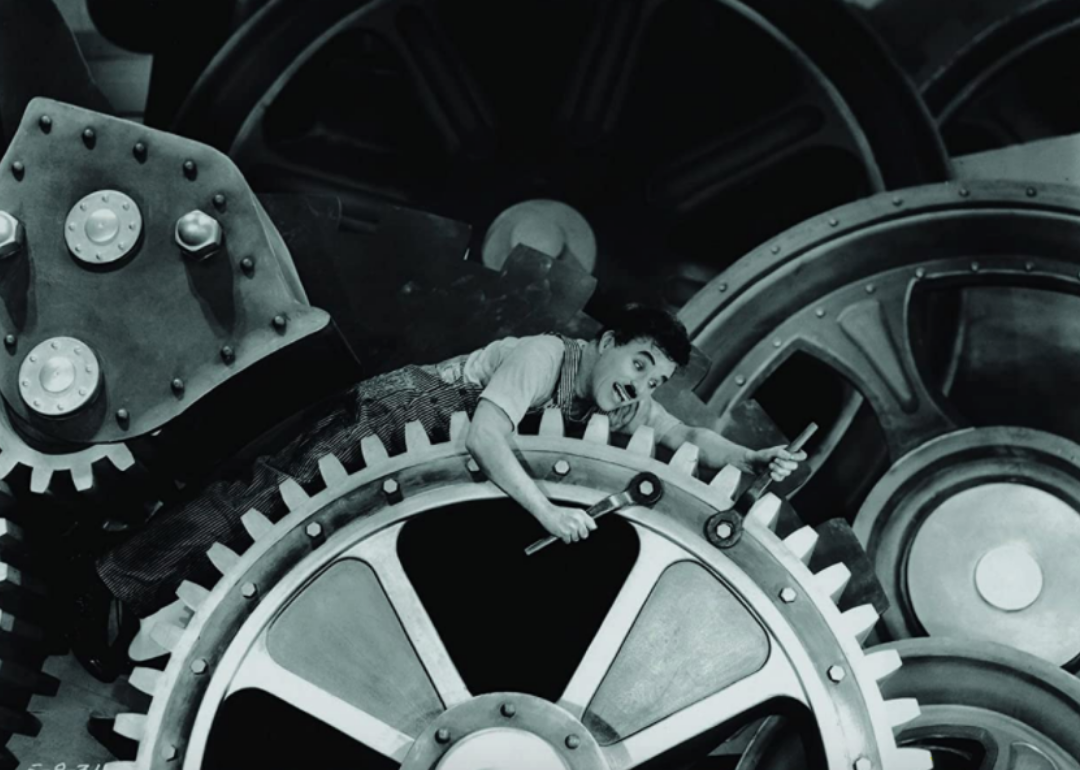 Charles Chaplin inside the wheels of a machine.