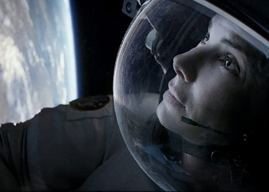 Sandra Bullock in a space suit floating above earth.