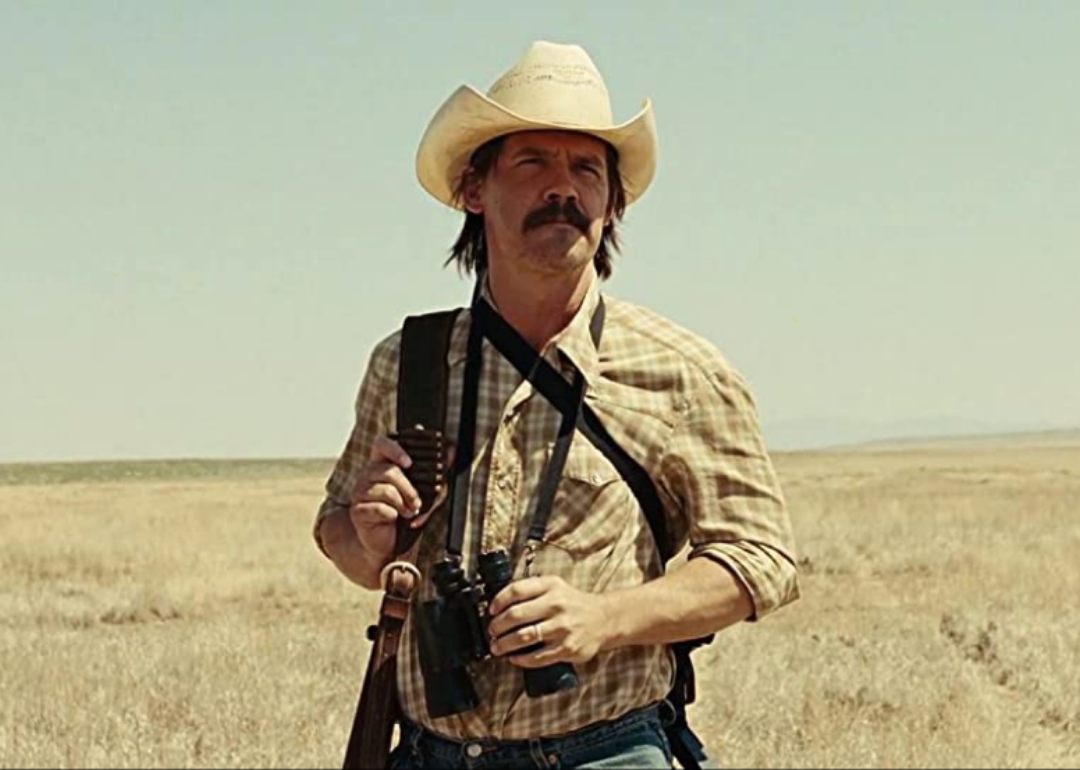 Josh Brolin in western wear in a field.
