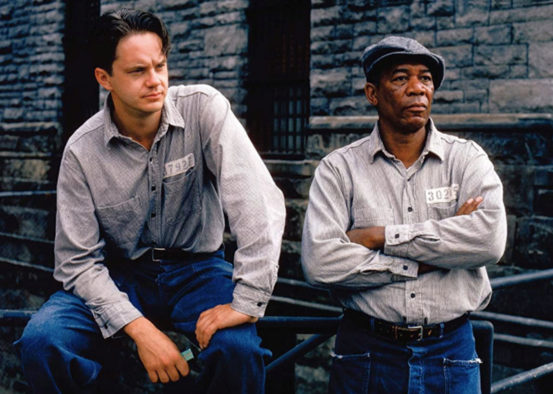 Tim Robbins and Morgan Freeman dressed in inmate shirts and jeans.