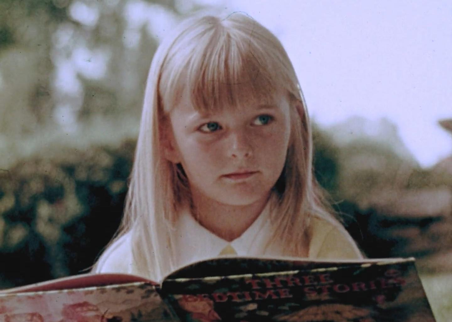 A little blonde girl holding a book of bedtime stories.
