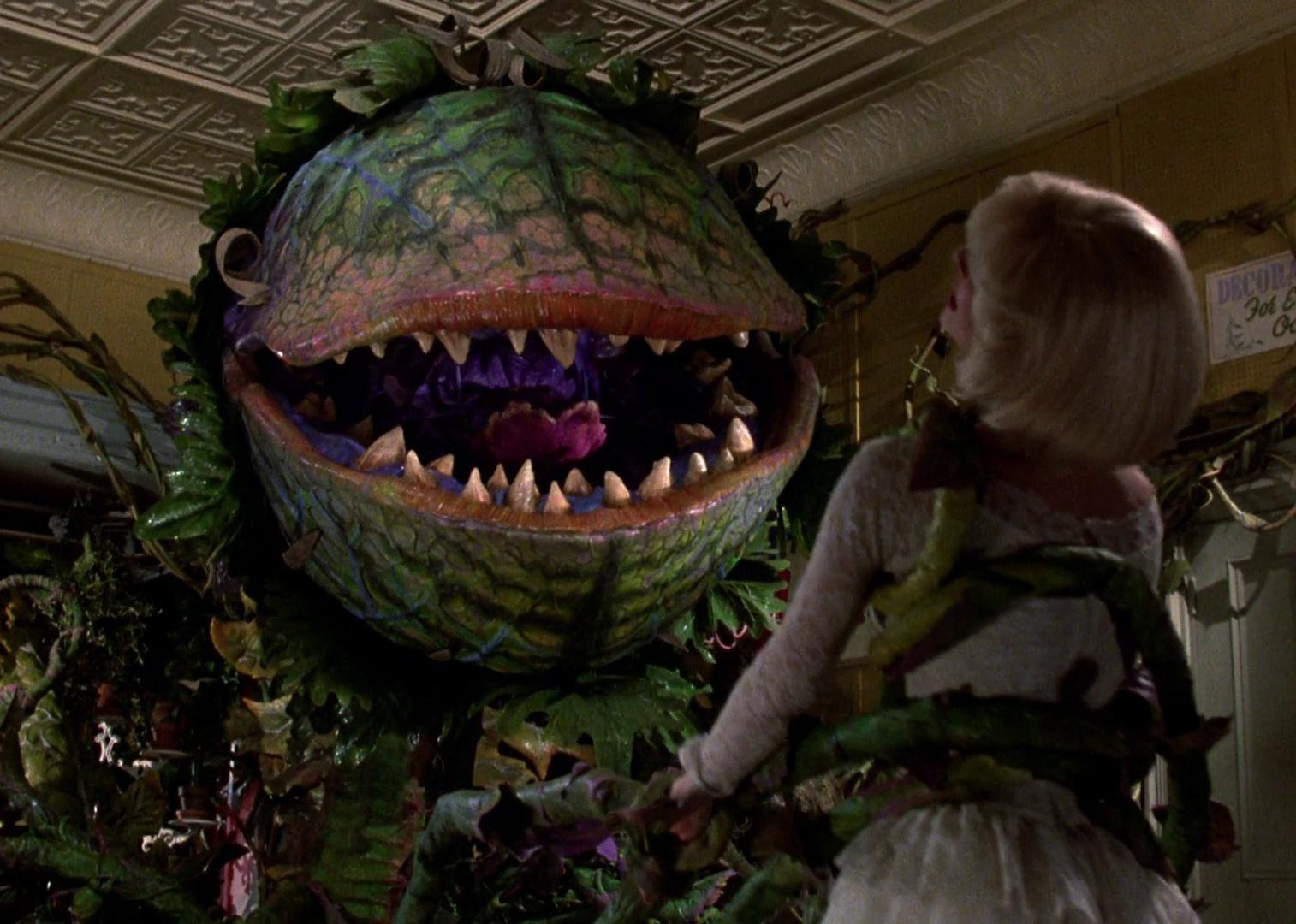 A monster that resembles a venus fly trap holds a woman in its tentacles.